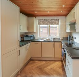 A kitchen with white cabinets a black countertop a microwave sink and stovetop at Maple in Dolton