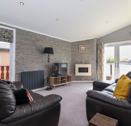 A living room with leather sofas a television and a fireplace at Capenwray in Carnforth