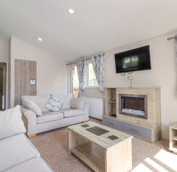 A living room with sofas a coffee table a wall mounted tv and fireplace at Coniston in Carnforth