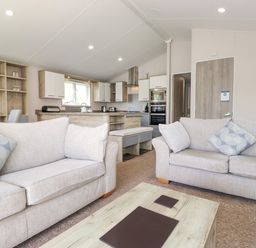 A living room with two sofas and a coffee table open to a kitchen with cabinets and appliances at Coniston in Carnforth