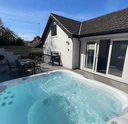 An outdoor patio area with a hot tub a metal table with six chairs and a barbecue grill at The Brambles in Monmouth