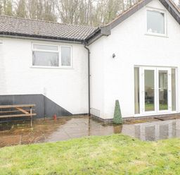 A white house with a tiled roof patio doors small grass area and a wooden picnic table at The Brambles in Monmouth