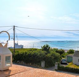 A coastal view with a white lantern on a balcony and houses near the sea at Swyn Llyr in Rhosneigr