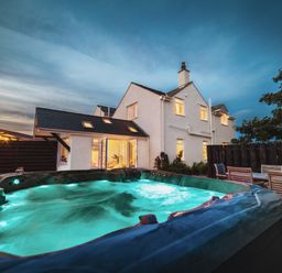 An outdoor area with a hot tub and house at Glanllyn Bach Llanfaelog