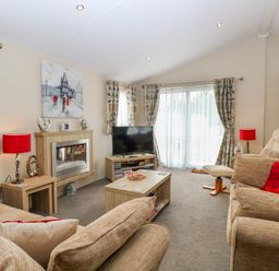 A living room with sofas a coffee table and a television at 21 Norman Drive Lodge in Burgh Castle
