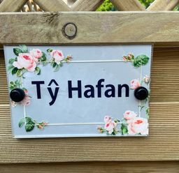 A wooden fence with a sign saying Ty Hafan decorated with pink roses at Ty Hafan in Mostyn