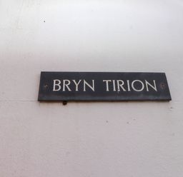 A black sign with white letters saying Bryn Tirion mounted on a white wall at Bryn Tirion in Morfa Nefyn