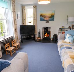 A living room with a fireplace a television two sofas and two small wooden chairs at Bryn Tirion in Morfa Nefyn