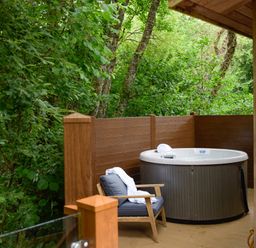 An outdoor deck with a hot tub and a chair with a white robe at 10 Stonerush Valley in Lanreath near Looe