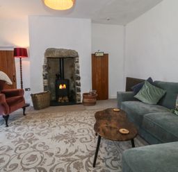 A living room with a sofa and an armchair at Tan Y Merddyn Ceunant near Llanrug