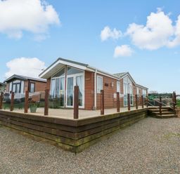 A wooden lodge with decking and steps at Gentle Tide in Hasguard Cross near Little Haven