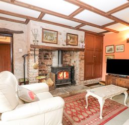 A living room with a fireplace a white armchair a coffee table with cards and a television at Loanview in Cornhill-On-Tweed