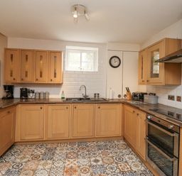 A kitchen with wooden cabinets a double oven a sink under a window patterned floor tiles and kitchen appliances at The Fullerton in Belsay