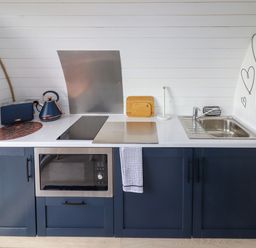 A kitchen counter with a microwave oven toaster kettle stovetop sink and cutting boards at Moel Famau in Bryniau Clwyd near Denbigh
