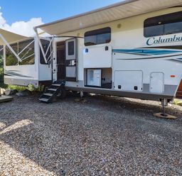 A recreational vehicle with awnings extended and steps leading to the door at Tickeydoo Tor Down Quarry in St Breward