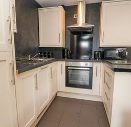 A kitchen with cabinets a sink an oven a microwave kettle and a toaster at The Buck in Llanerch Park near St Asaph