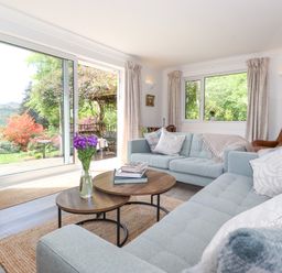 A living room with blue sofas and a wooden coffee table with books and flowers at Sweden Bridge Cottage in Ambleside