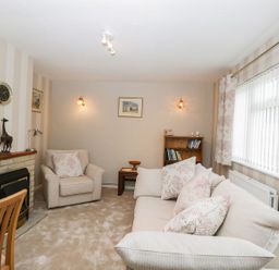 A living room with a sofa armchair fireplace clock bookshelf and dining table at Ground Floor Annex in Milton-Under-Wychwood