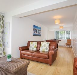A living room with brown leather sofas a wicker coffee table and a foosball table at Mor Glas in Abersoch