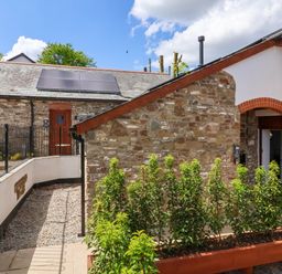 A courtyard with stone buildings and plants in a planter at Ladybird Rest in Parkham near Bideford
