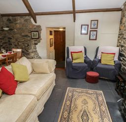 A living room with armchairs a sofa dining table and stone walls at The Old Stable in Pontfaen near Fishguard