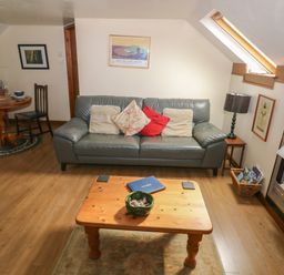 A living room with a gray sofa and cushions wooden coffee table lamp and fireplace at The Loft in Pontfaen near Fishguard