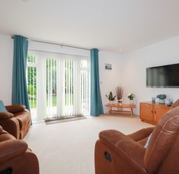 A living room with a sofa and television at Blissful Ocean Breeze in Perranporth