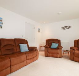 A living room with brown furniture and photographs on the wall at Blissful Ocean Breeze in Perranporth