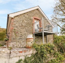 Stone house with a small metal balcony and vintage milk churn outside at Field View in Llanybydder