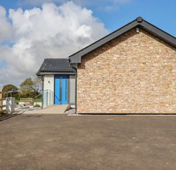 An outdoor view of a house with stone wall and blue door at Lake View Kestle Mill near Quintrell Downs