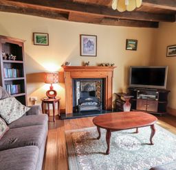 A living room with a sofa a wooden coffee table a fireplace a television and a bookshelf at Castell Y Garn near Newport Beach Pembrokeshire