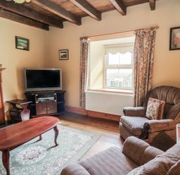 A living room with armchairs a wooden coffee table and a television near a window at Castell Y Garn near Newport Beach Pembrokeshire