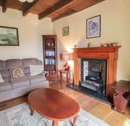 A living room with a sofa a wooden coffee table a fireplace a lamp and a bookshelf at Castell Y Garn near Newport Beach Pembrokeshire