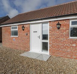Exterior view of a brick cottage with a white door and two windows at Doubletree Cottage in Swainsford near Mere