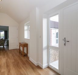 An entryway with wooden flooring a small wooden table a white door and a wall decoration at Doubletree Cottage in Swainsford near Mere