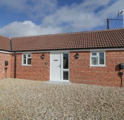 A one-story brick house with a tiled roof and three windows and a white door at Singletree Cottage in Swainsford near Mere