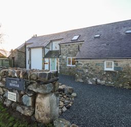 A stone house with a gravel driveway at Llys Bennar in Dyffryn Ardudwy