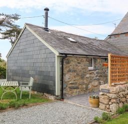 A stone and slate cottage with a small garden table and bench outside at Y Stabl in Dyffryn Ardudwy