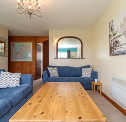 A living room with blue sofas a wooden coffee table and a wall mirror at Skylarks Trevellas Nr St Agnes