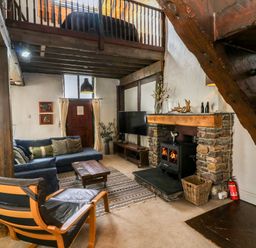 A living room with wooden beams a fireplace and seating at The Old Smithy in Lynton