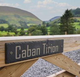 A sign labeled Caban Tirion with mountains and greenery in the background at Caban Tirion in Dinas Mawddwy near Dolgellau