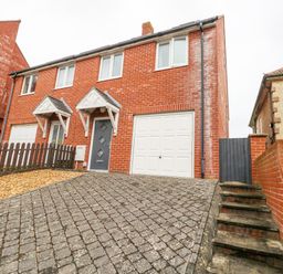 A brick semi detached house with a driveway garage and stairs leading to a gate at Dotties Retreat in Weymouth