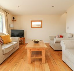 A living room with beige sofas wooden coffee table and a TV at The Willows in Winnard's Perch near St Columb Major