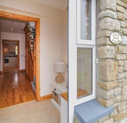 An entrance hallway with wooden floor and stairs decorated with flowers at 46 Dunalinn in Culdaff County Donegal