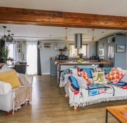 A living room with a sofa and kitchen island at Coogee View in Maenygroes near New Quay