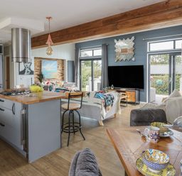 A kitchen and living area with bar stools and a television at Coogee View Maenygroes near New Quay