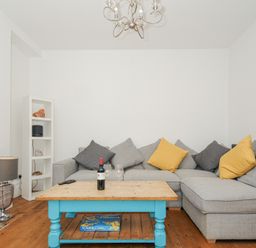 A living room with a grey sectional sofa and a wooden coffee table with a bottle of wine and glasses at Albert House in Looe
