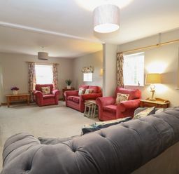 A living room with red armchairs and a grey sofa at Flint Cottage in West Caister near Caister-on-Sea
