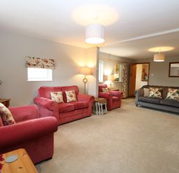 A living room with pink and gray sofas floral cushions and lamps at Flint Cottage in West Caister near Caister-on-Sea