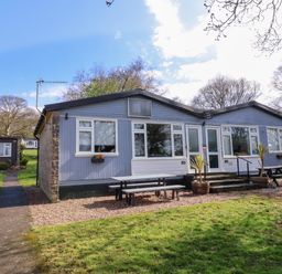 A single-story building with picnic tables outside on a grassy area at Number 24 The Park in Kilkhampton